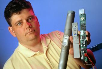 Researcher Jeff Moore holds environmental monitors that contain integrated optic interferometric sensors developed at GTRI, 1998.