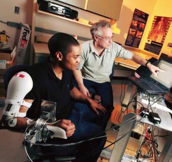 A student intern works with GTRI's Dinal Andreasen on an exoskeleton that can be used to help rehabilitate injured people quicker and more effectively, 2006.